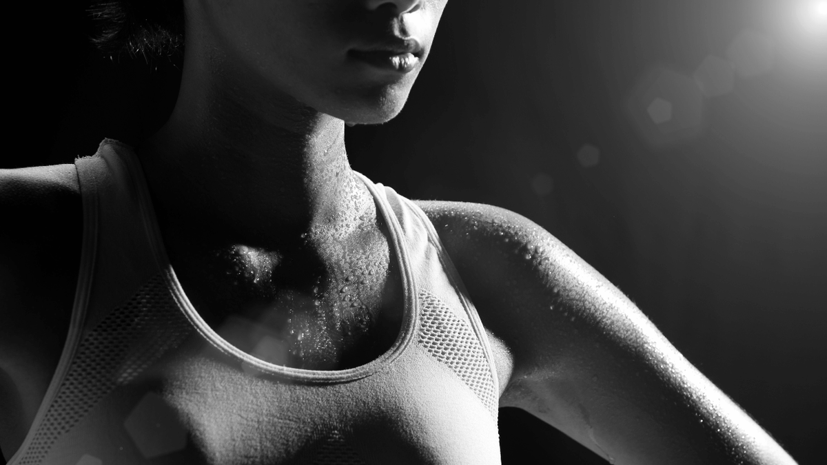 Black-and-white close-up of a female athlete covered in sweat after intense training, illustrating heat accumulation, exertion and thermoregulation during performance.