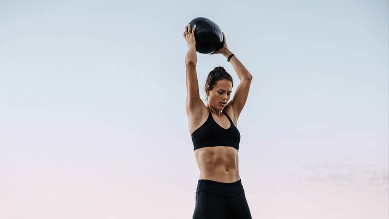 Athlete performing a high-intensity medicine ball exercise outdoors, illustrating repeated effort, thermoregulation, and recovery between intervals.