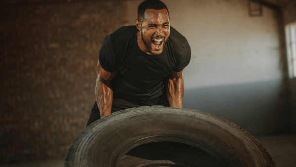 Exhausted athlete flipping a tire during high-intensity functional training, illustrating heat accumulation, repeated effort, and physical strain.