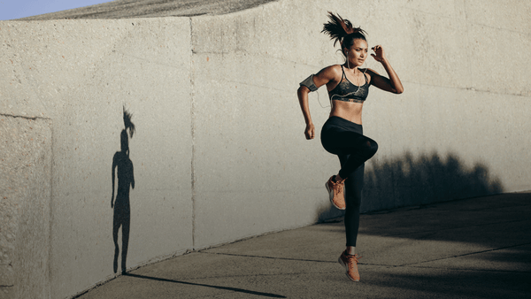 Female athlete performing explosive running drills outdoors during high-intensity training focused on endurance, thermoregulation and repeated efforts.