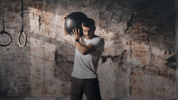 Male athlete performing medicine ball training in a gym environment during functional fitness and repeated high-intensity efforts.